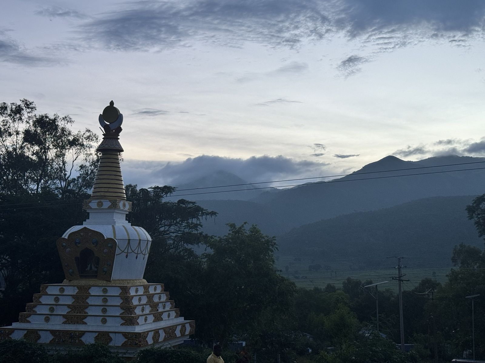 Silhouette of a stupa at dusk with blue misty hills and soft clouds